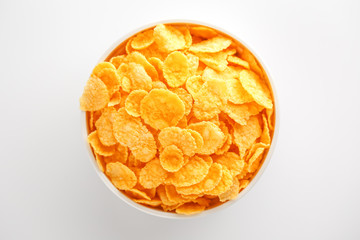 White cup with golden corn flakes isolated on white background. View from above. Delicious and healthy breakfast