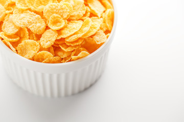White cup with golden corn flakes isolated on white background. View from above. Delicious and healthy breakfast