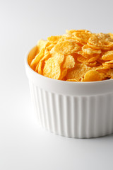 White cup with golden corn flakes isolated on white background. View from above. Delicious and healthy breakfast
