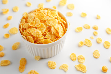White cup with golden corn flakes, isolated on white background. Hopya crumbled around the cup. View from above