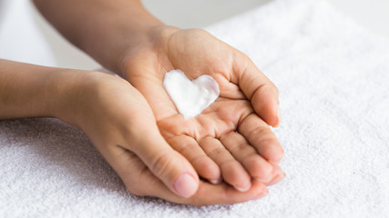 Love your body. Female hands with cream in heart shape