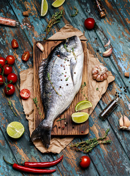 Fresh fish dorado. Raw dorado fish and ingredient for cooking. Fresh fish gilt-head bream dorade with salt, herbs and pepper.