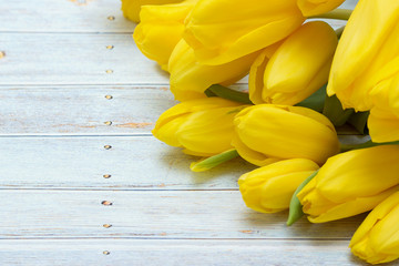 Bouquet of yellow tulips on a blue wooden background.
