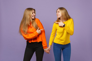 Two young blonde twins sisters girls in vivid clothes holding ha