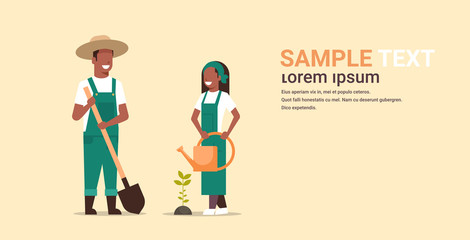 couple farmers planting tree man with shovel woman holding watering can african american gardeners working in garden agricultural gardening concept full length copy space horizontal