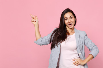 Portrait of cheerful pretty young woman in striped jacket pointing index finger aside up isolated on pink pastel background in studio. People sincere emotions, lifestyle concept. Mock up copy space.