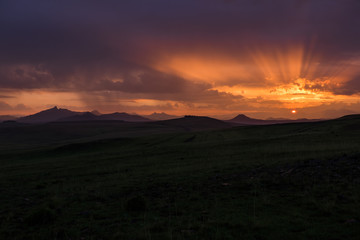 Sunrise landscape with mountains, clouds, orange sky and sun beams, Lesotho, Africa