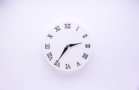 Round clock with a white dial on a white background. Minimal concept. Flat lay. View from above