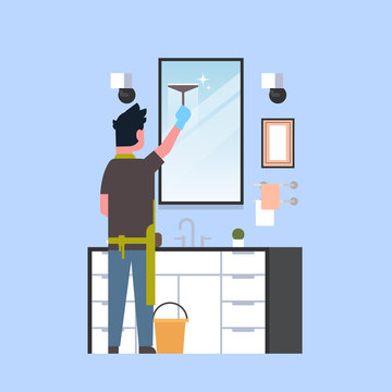 man in gloves and apron cleaning mirror with squeegee guy in bathroom doing housework concept rear view male character full length