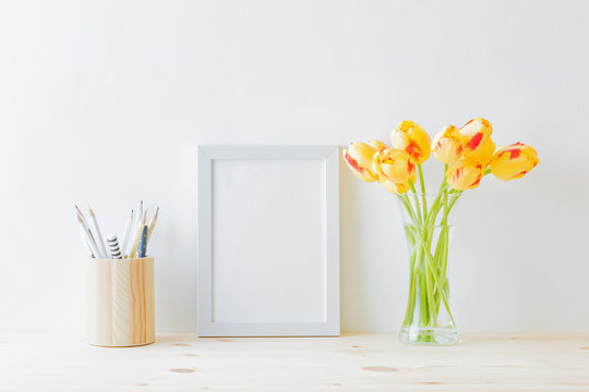Mockup with a white frame and yellow tulips in a vase on a light background