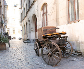 Old wooden cart on a city street against a wall with a painting