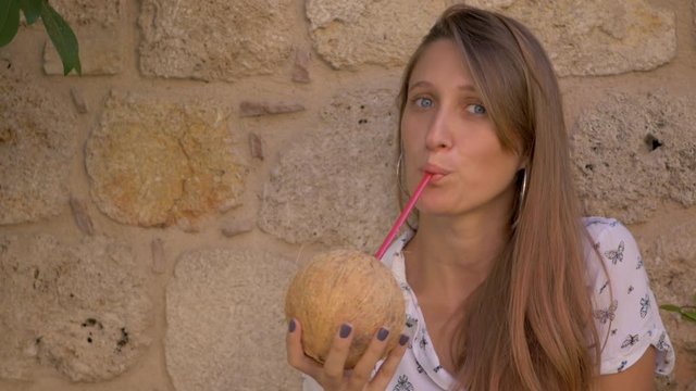 Young smiling woman drinking coconut water