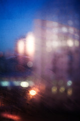 Fototapeta na wymiar Blurred background with lights of the evening city through the window