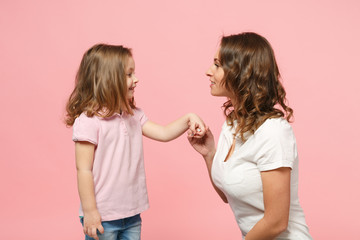 Woman in light clothes have fun with cute child baby girl. Mother, little kid daughter isolated on pastel pink wall background, studio portrait. Mother's Day, love family, parenthood childhood concept