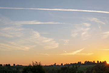 beautiful sunset above the village. scenic countryside landscape. clouds and sun in the sky