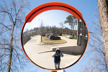 The image of the photographer and cars on the traffic curve mirror