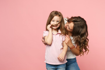 Woman in light clothes have fun with cute child baby girl. Mother, little kid daughter isolated on pastel pink wall background, studio portrait. Mother's Day, love family, parenthood childhood concept