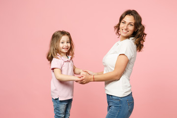 Woman in light clothes have fun with cute child baby girl. Mother, little kid daughter isolated on pastel pink wall background, studio portrait. Mother's Day, love family, parenthood childhood concept