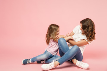 Woman in light clothes have fun with cute child baby girl. Mother, little kid daughter isolated on pastel pink wall background, studio portrait. Mother's Day, love family, parenthood childhood concept