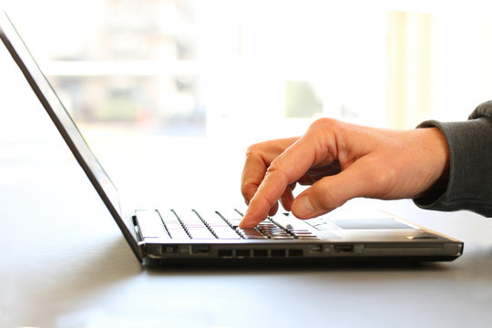 Closeup image of a finger touching texting on keyboard on a laptop computer. Stock photo with white background for copy space.