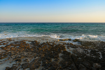 evening sea landscape with turquoise sea and rocky shore