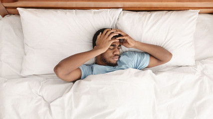 Restless african american man waking up with headache