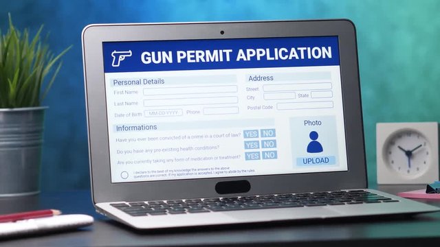 Laptop computer with a gun permit form on its display. Camera turning slowly around the desk.