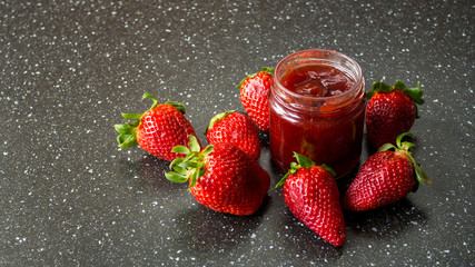 Dżem truskawkowy w otoczeniu świeżych truskawek