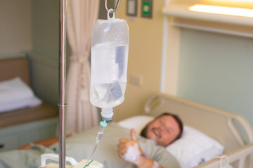 Close-up. Male hand with a dropper during chemotherapy in a hospital. The man is in the hospital room, without focus. Health is a topic of health and healing.