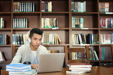 African American student with laptop studying in library