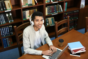 African American student with laptop studying in library