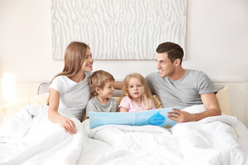 Fototapeta premium Happy family reading book in bed at home