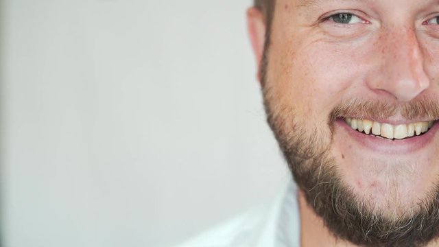 Handsome Caucasian man with a beard smiling on a white background, portrait of a man half face.