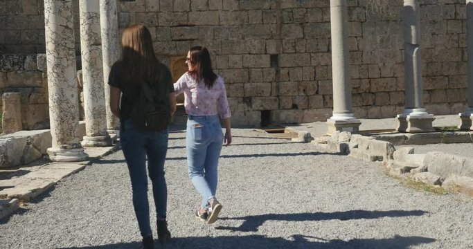 Young female tourists walking in Ancient city Perge, open air antique historical museum