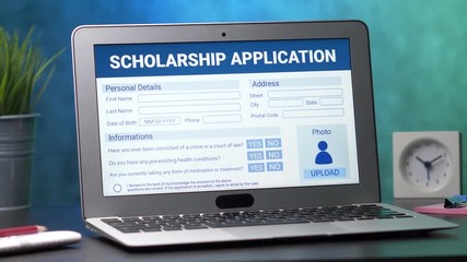 Laptop computer with a scholarship application form on its display. Camera turning slowly around the desk.