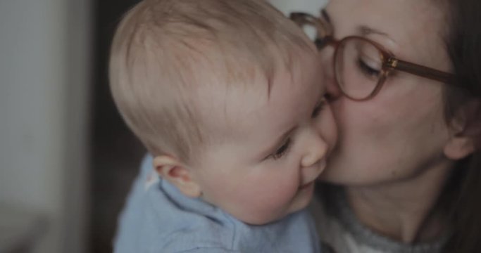 Portrait of mother kissing little baby girl