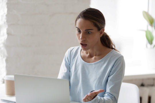 Shocked and stressed woman looking at laptop screen