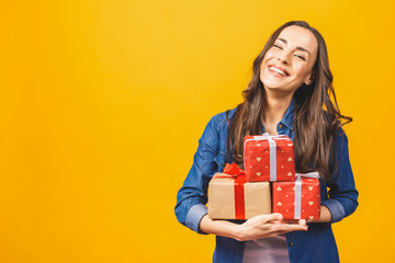 Young smiling model hold gift box. Woman isolated on yellow background.
