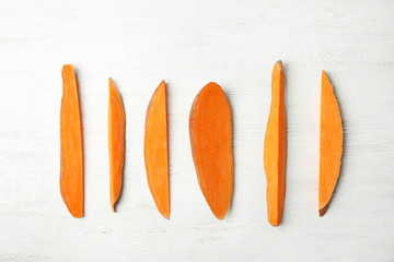 Flat lay composition with slices of sweet potato on white wooden background