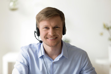 Portrait of handsome smiling man working in headphones at office