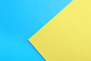 Blue and yellow paper sheets as colorful background, top view