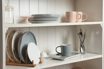 Stylish storage stand with different ceramic dishware at home