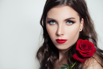 Fototapeta na wymiar Cute model woman with red lips makeup holding red rose flower