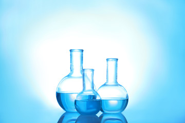 Laboratory glassware with liquid on color background. Solution chemistry