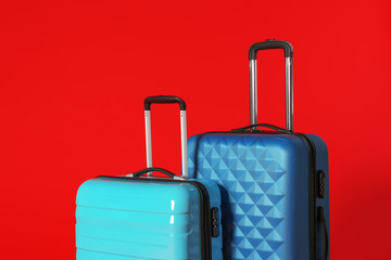 Stylish modern suitcases with handles on color background