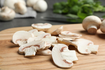 Wooden board with sliced raw mushrooms on table, closeup
