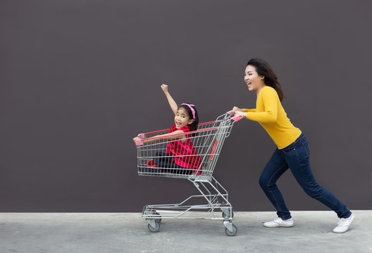 Happy Mom And Kid Go Shopping Cart Together.