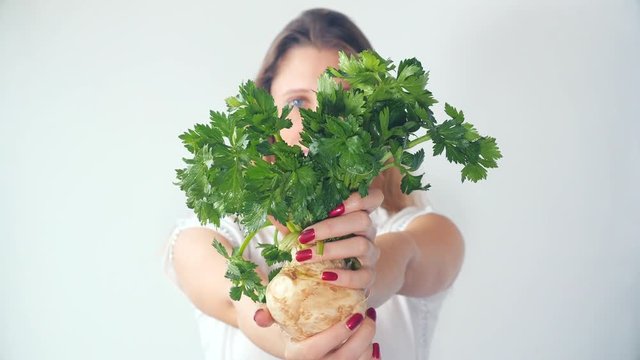 Defocused young woman showing fresh celery root