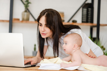 Young mother with baby infant and laptop