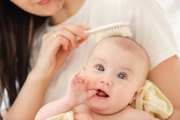 Close up of female hand combing hair baby.